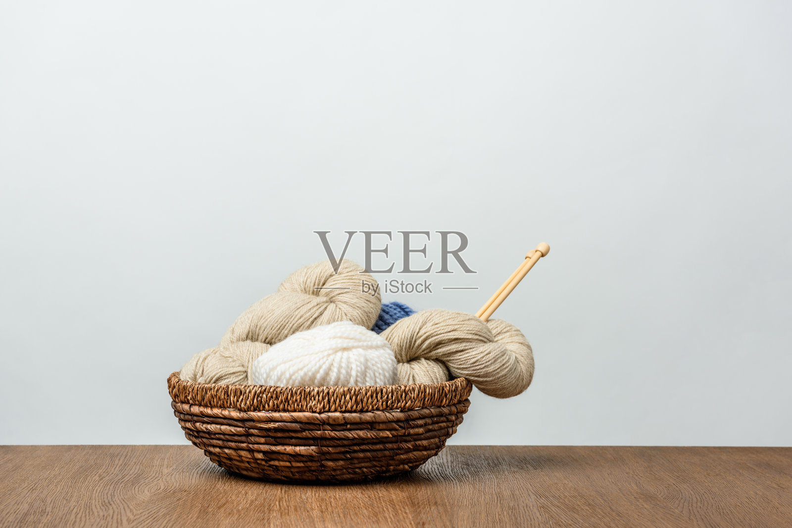 近距离观看纱线与编织针柳条篮子在木制桌面上灰色的背景照片摄影图片