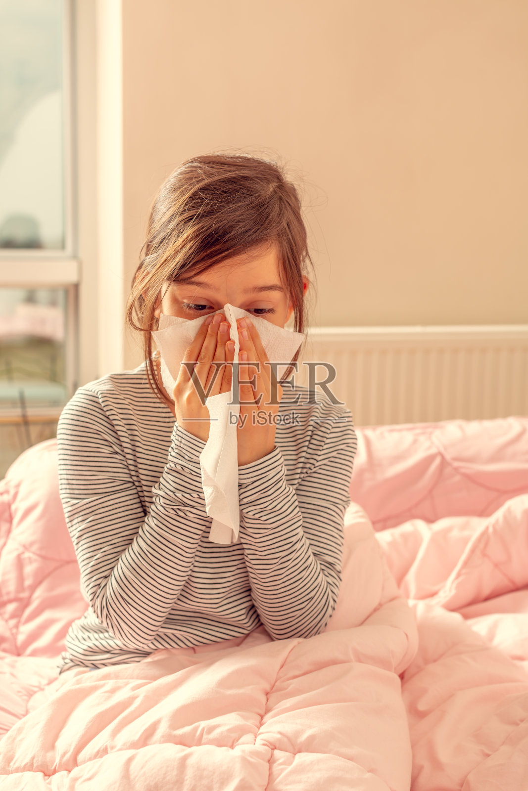 生病的小女孩躺在床上擤鼻涕照片摄影图片