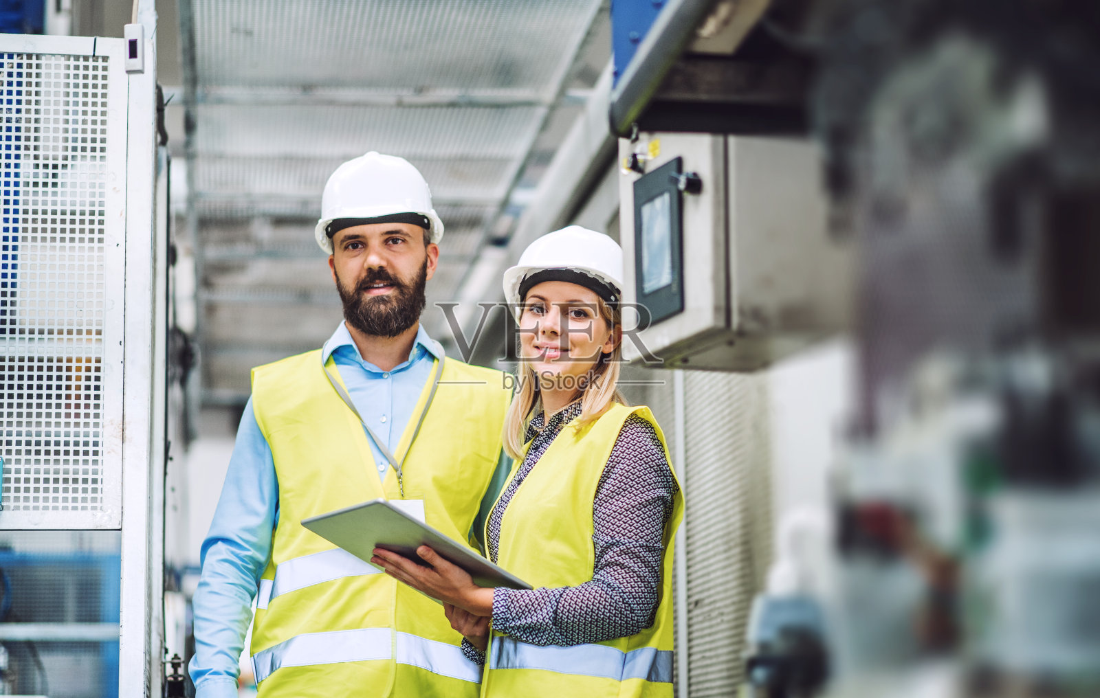 一幅在工厂里拿着平板电脑的男工程师和女工程师的肖像。照片摄影图片