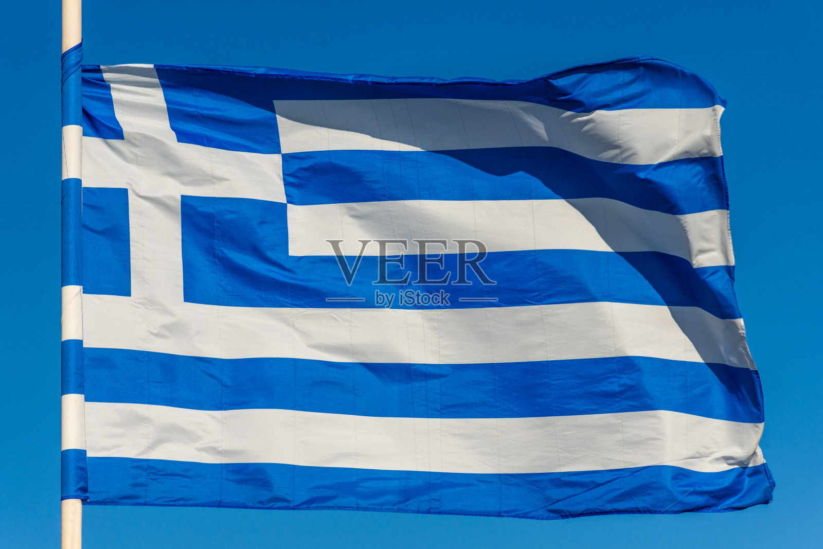 旗杆上的希腊国旗在蓝色背景上飘扬照片摄影图片