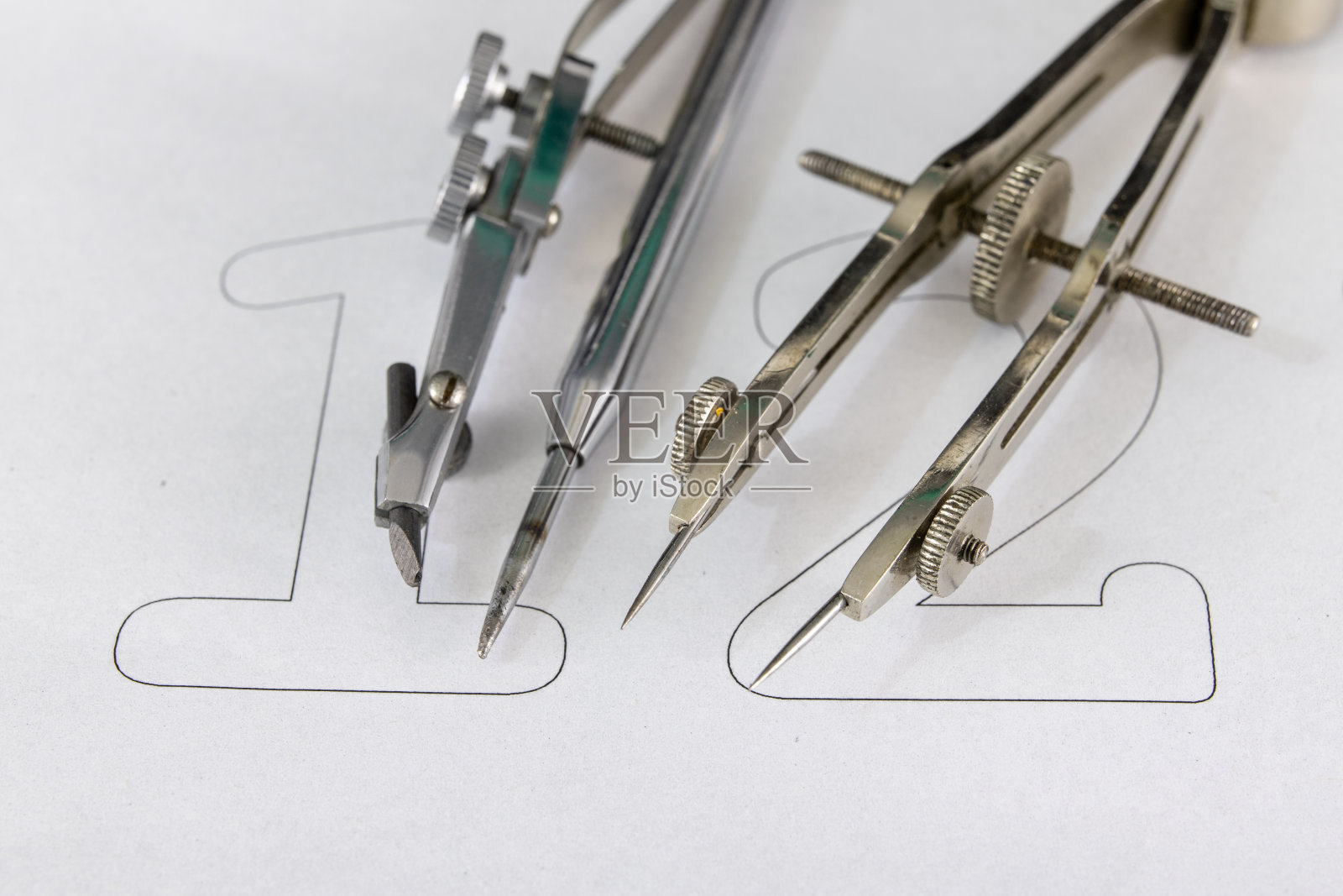 一个在白纸上画圆圈的同伴。用于绘制技术图纸的绘图附件。光背景。照片摄影图片