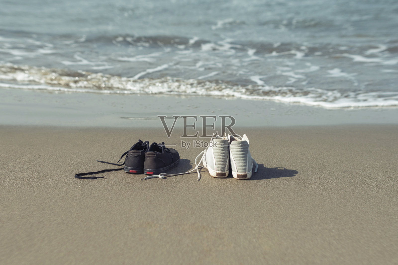 黑色和白色的运动鞋上的沙滩上的海的背景。照片摄影图片