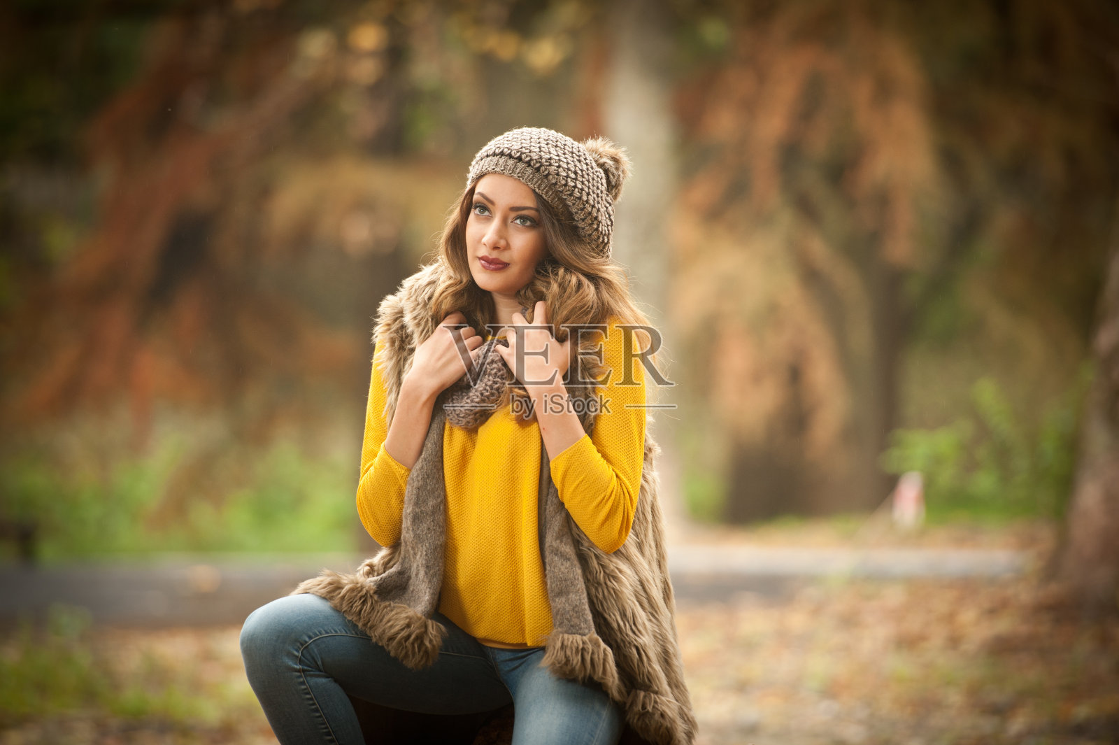 一个漂亮的年轻白种女子戴着红色的帽子和围巾,穿着黄色的套衫在秋天的公园里,红绿黄三。秋,季节和人的概念。秋天的生活方式照片摄影图片