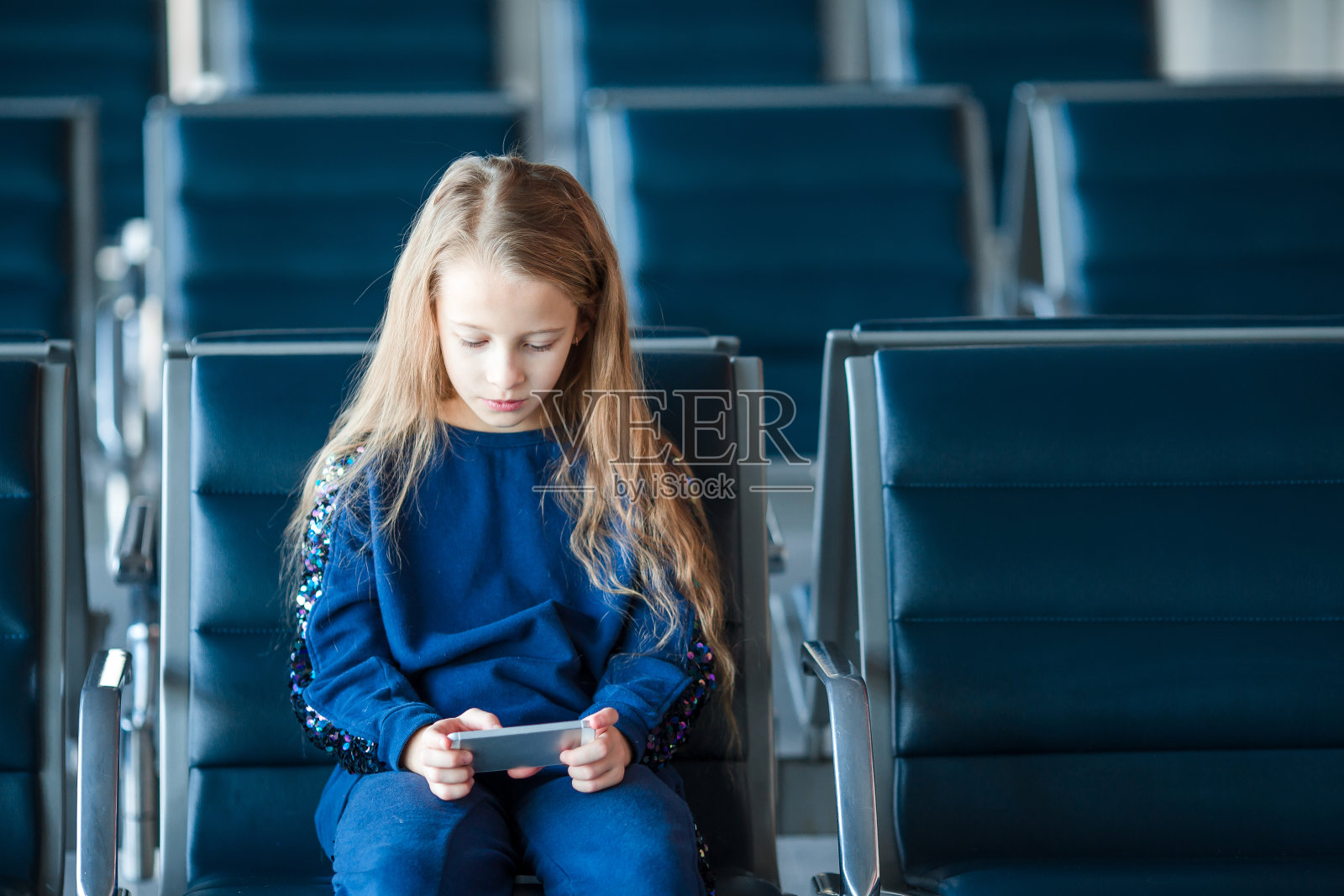 在机场等待登机的可爱小女孩玩着笔记本电脑照片摄影图片