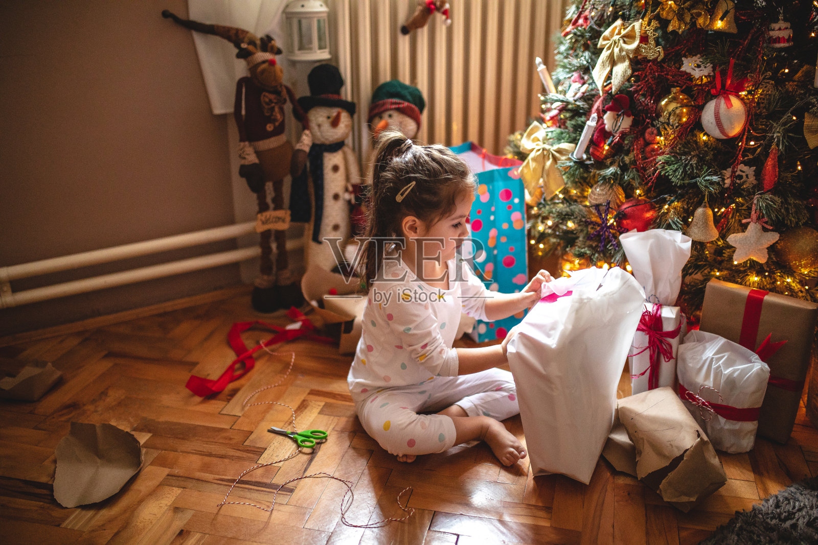 美丽的蹒跚学步的小女孩正在拆礼物照片摄影图片
