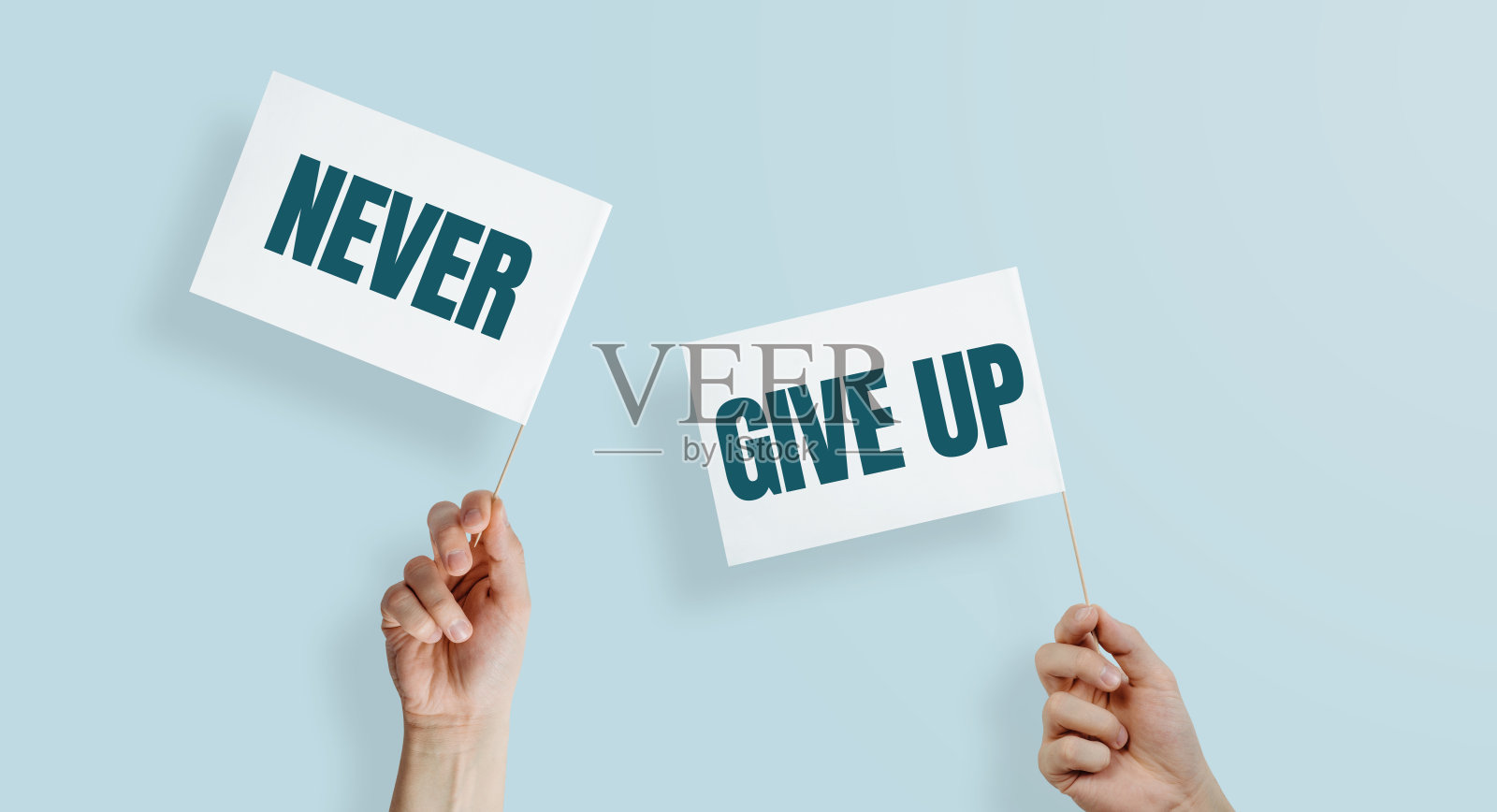 两只手举着写着“永不放弃”的白旗。照片摄影图片