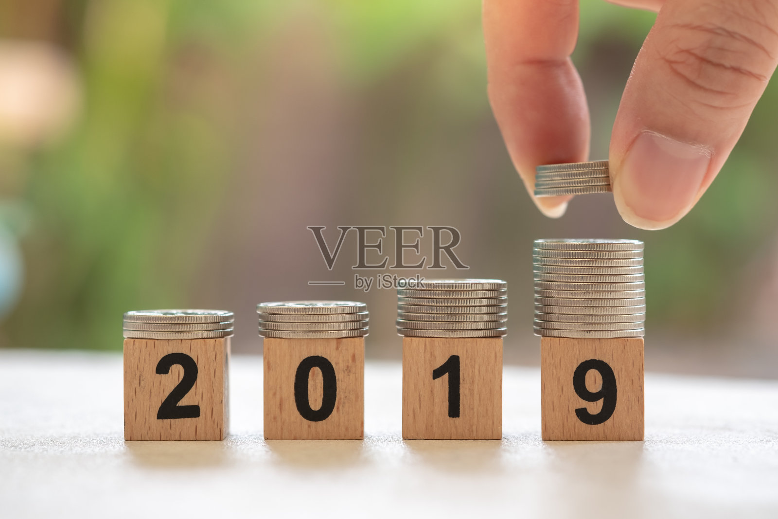2019年新年,节约理念。紧叠的银币在数字木块上与人的手,并把一叠硬币在堆栈的顶部照片摄影图片