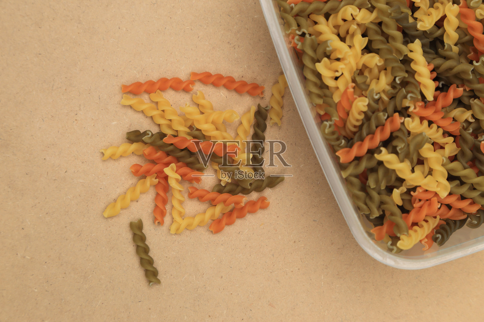 生的三色螺旋扭曲通心粉在托盘和分散的背景。照片摄影图片