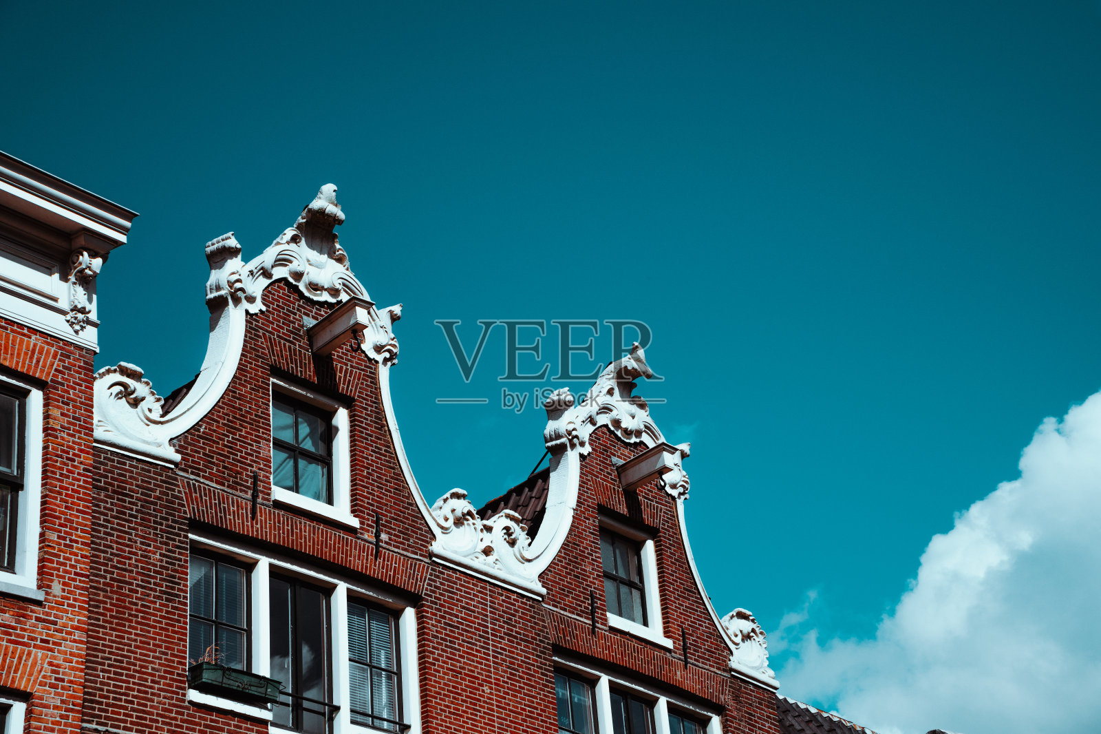 阿姆斯特丹的蓝天映衬下的老建筑立面和屋顶装饰的特写。建筑细节北荷兰照片摄影图片