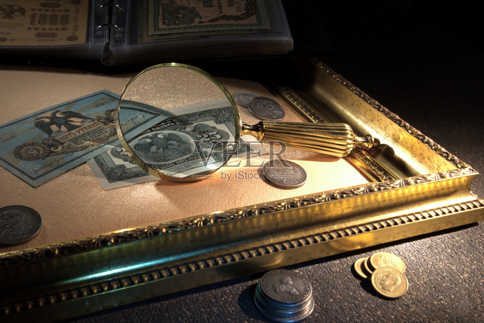 用放大镜看旧钱和硬币。钱币和收集钱。俄罗斯帝国和世界货币,银,金。照片摄影图片