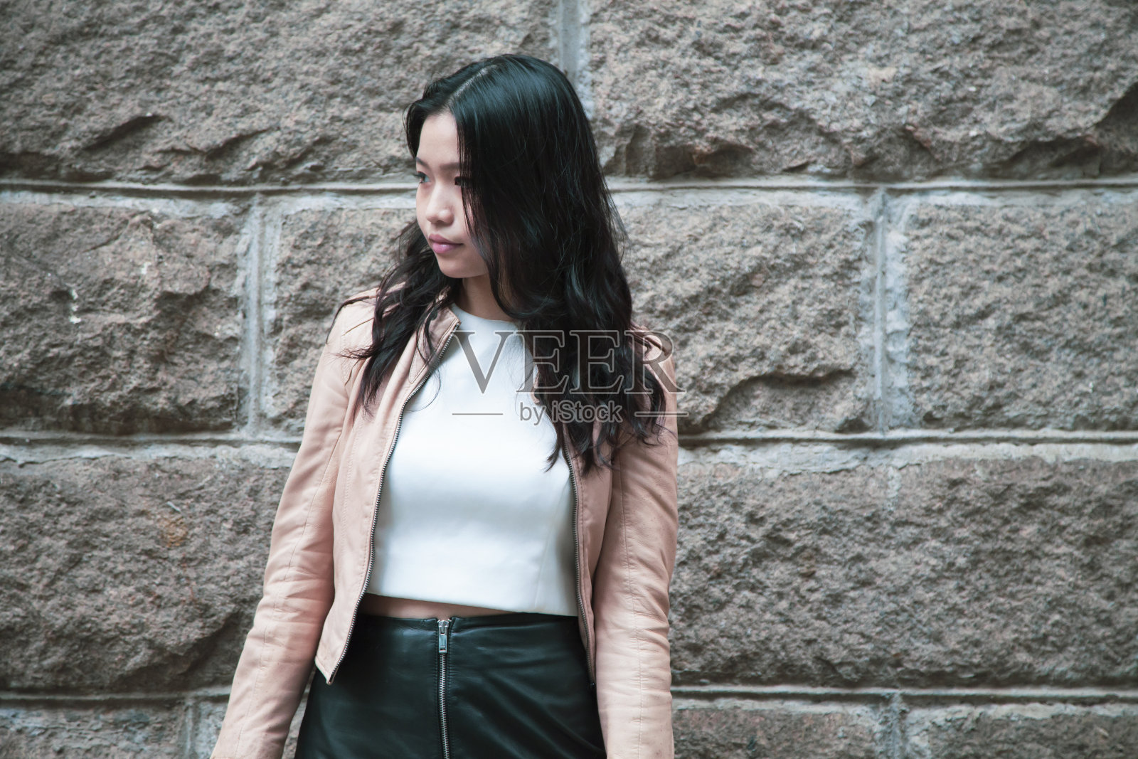 年轻女子正站在墙前照片摄影图片