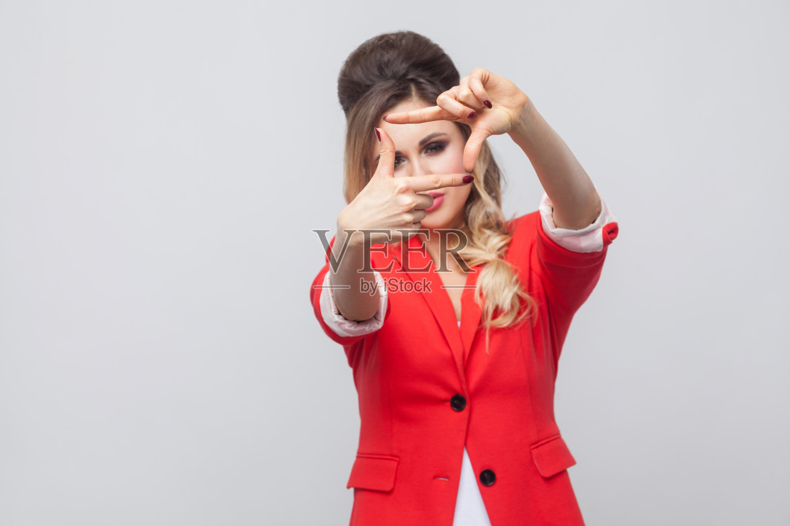 肖像美丽的商务女士的发型和化妆在红色花哨的西装外套,站着看相机与裁剪构图手势。照片摄影图片