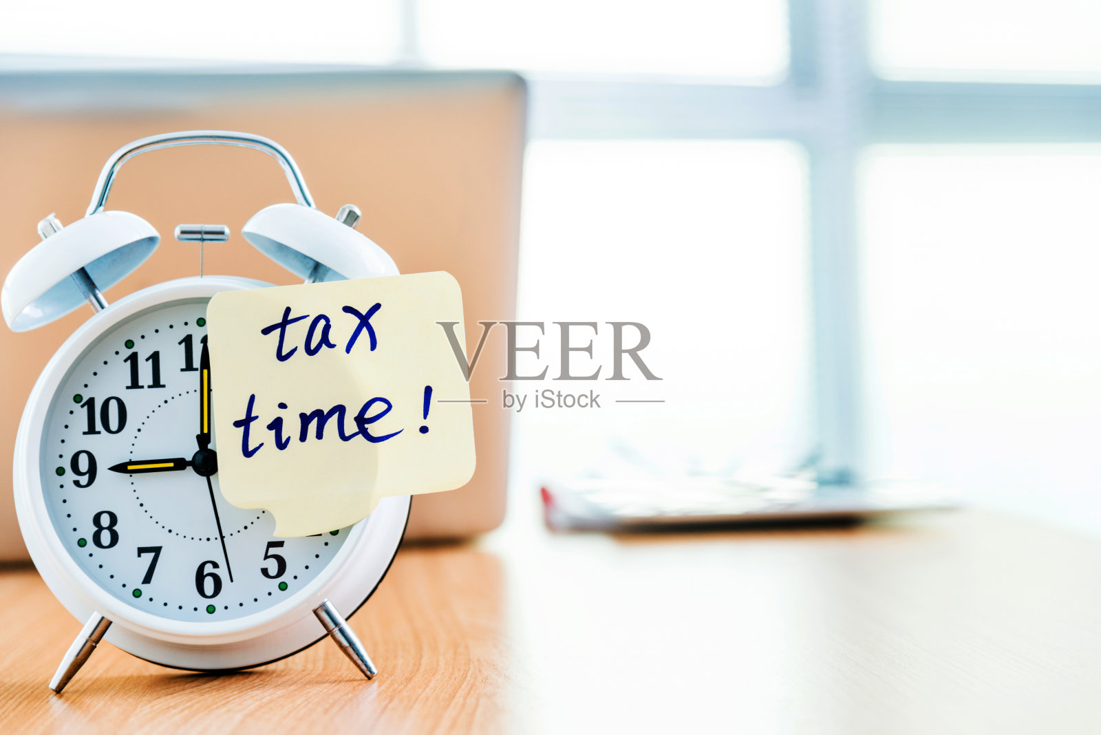 办公室桌子上的一个钟,上面贴着缴税时间的便签照片摄影图片