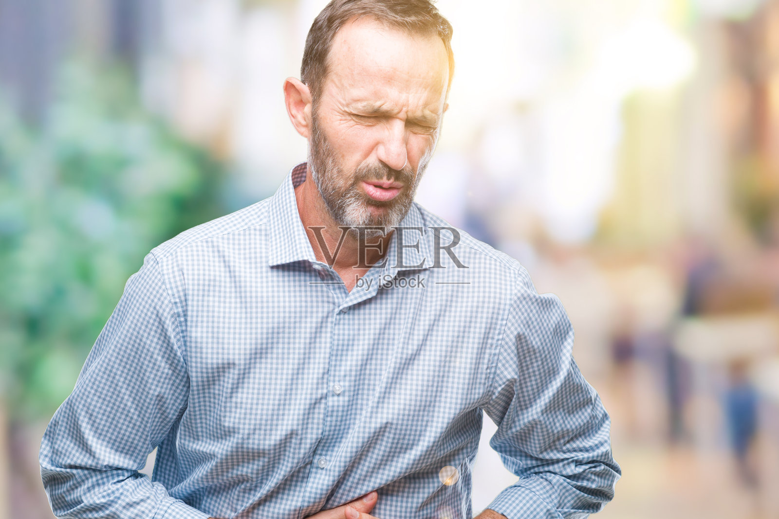 中年白发苍苍的资深商务人士过孤背景,手抚胃因恶心、痛病感觉不适。疼痛的概念。照片摄影图片