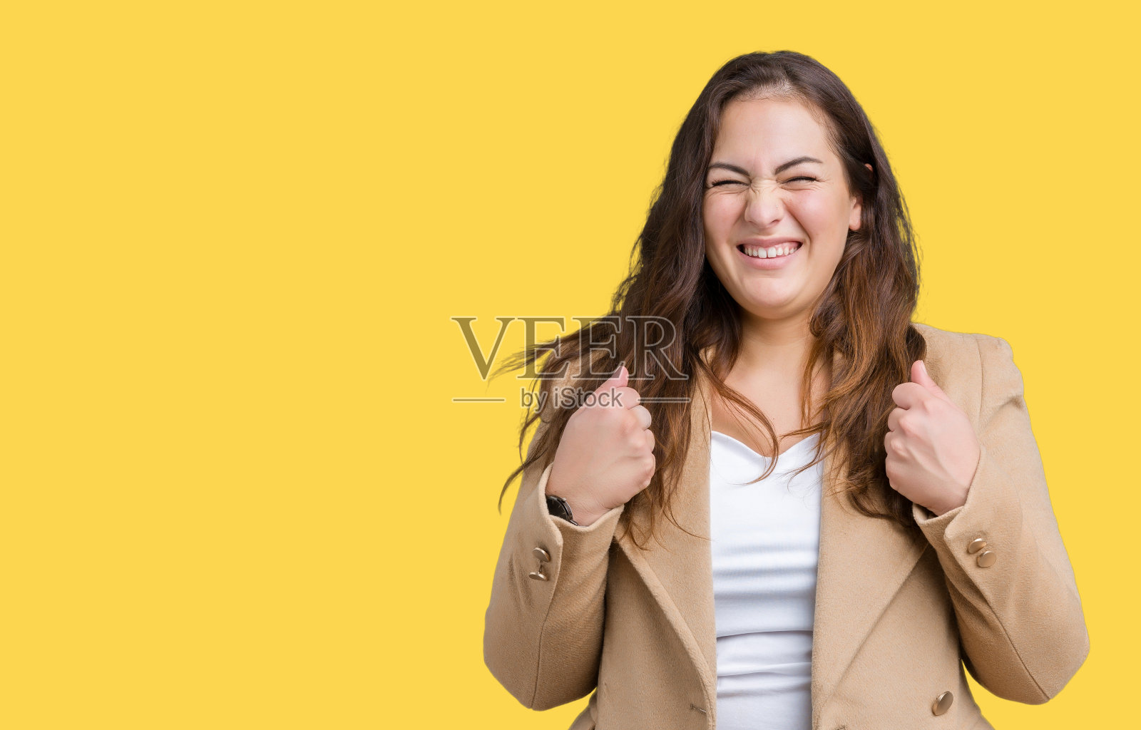 美丽的加码年轻女子穿着冬季大衣在孤立的背景兴奋的成功与双臂举起庆祝胜利微笑。赢家的概念。照片摄影图片