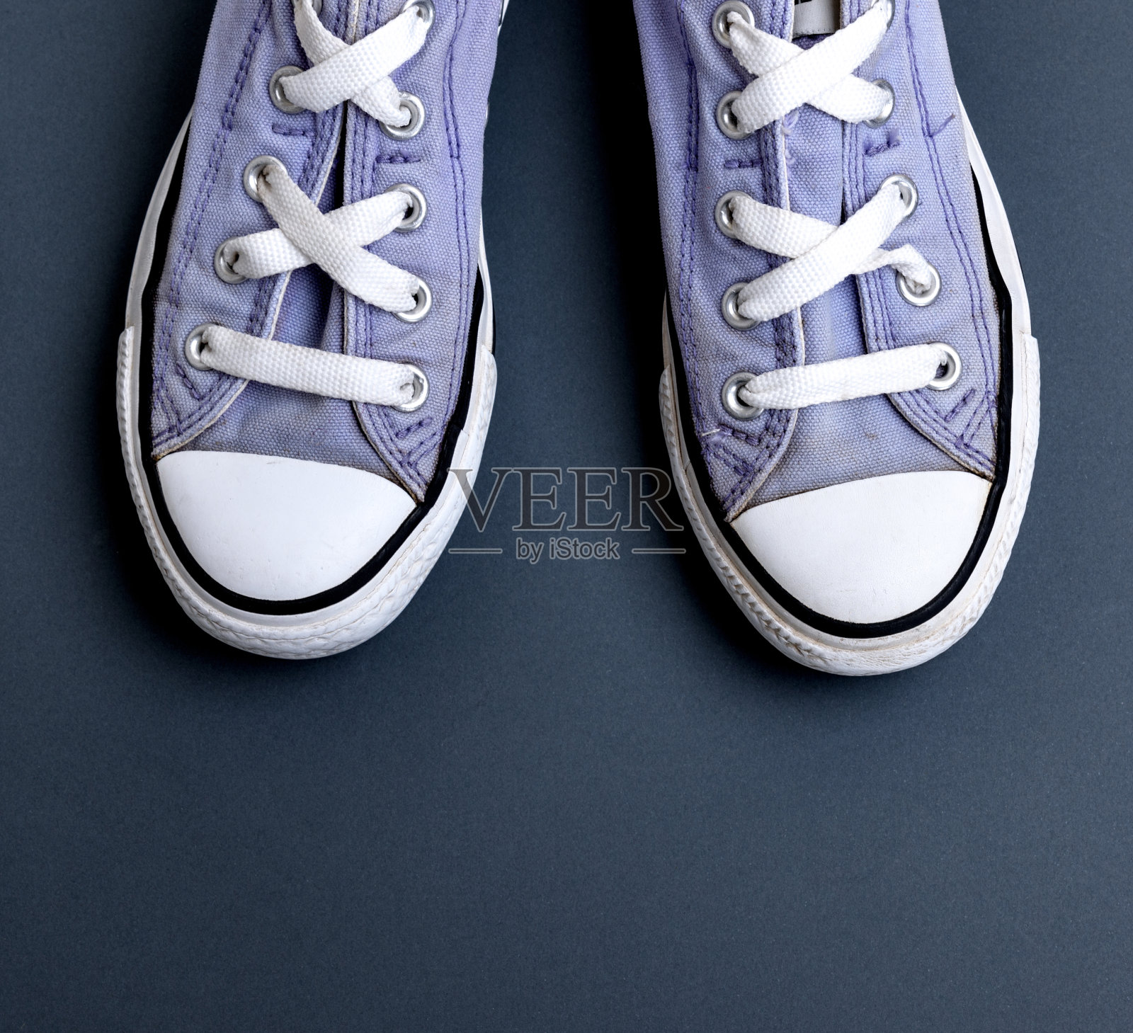 一双破旧的旧纺织品淡紫色运动鞋与白色鞋带照片摄影图片