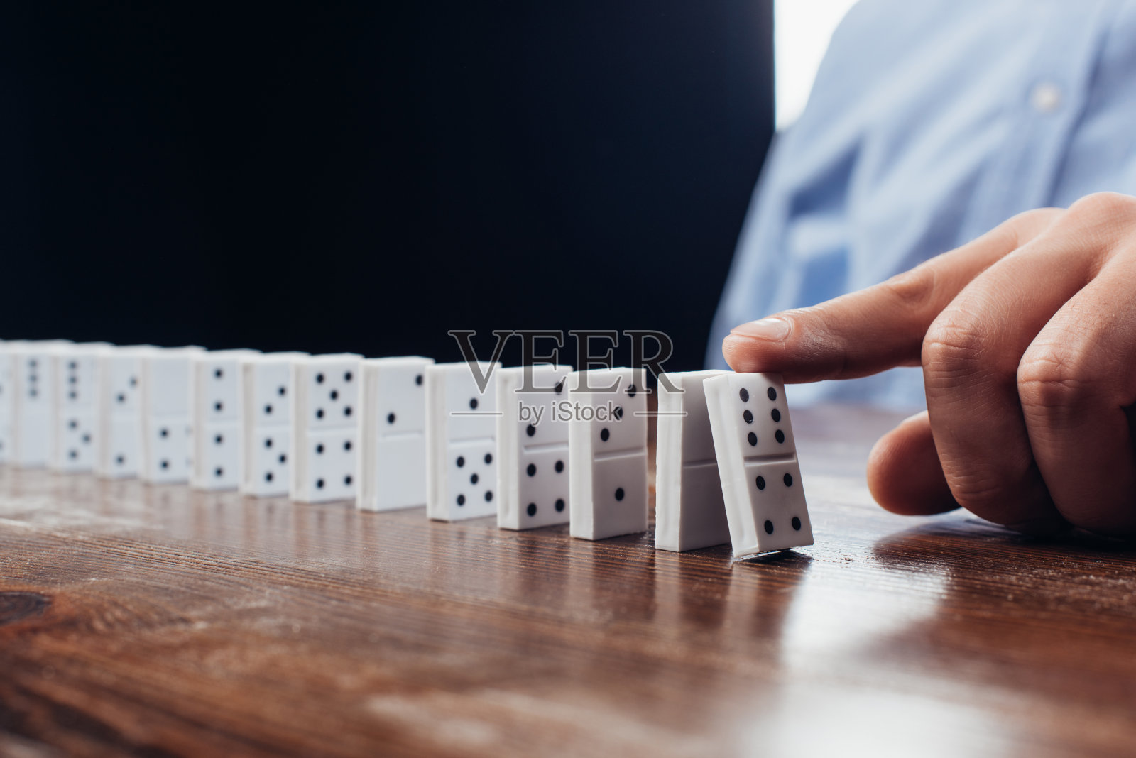 近距离观看男子推多米诺排在木桌上照片摄影图片