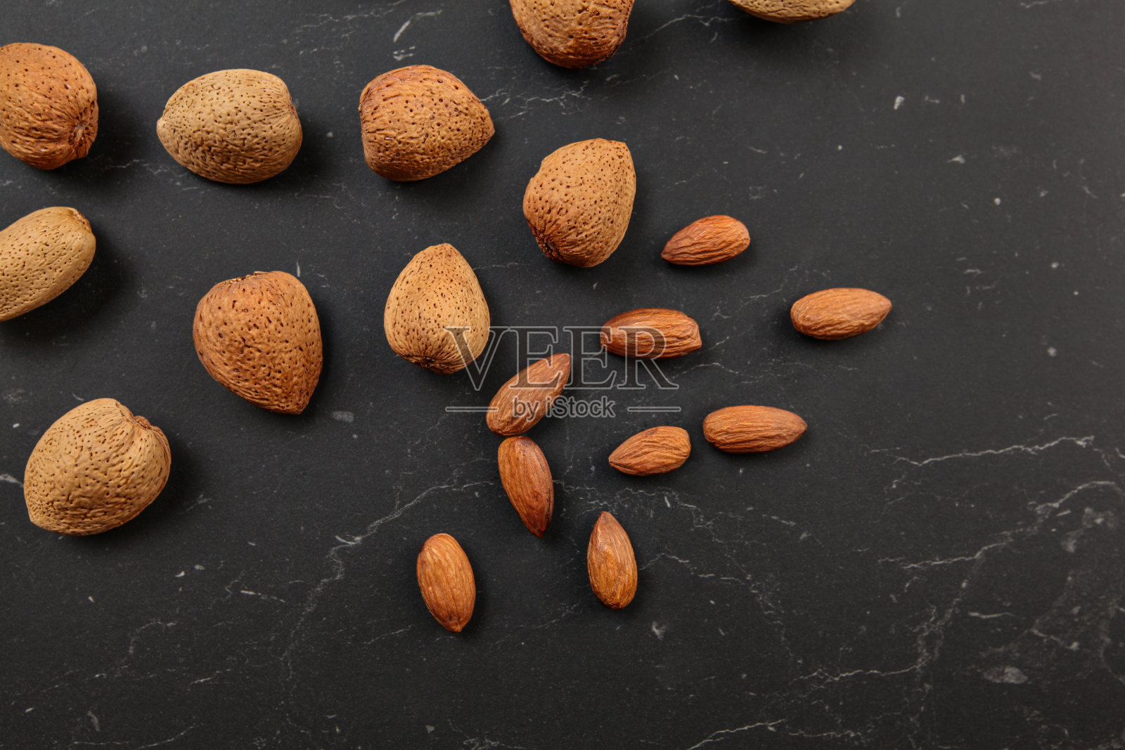 从上往下看,杏仁,整个和开裂,在深色大理石板上。照片摄影图片