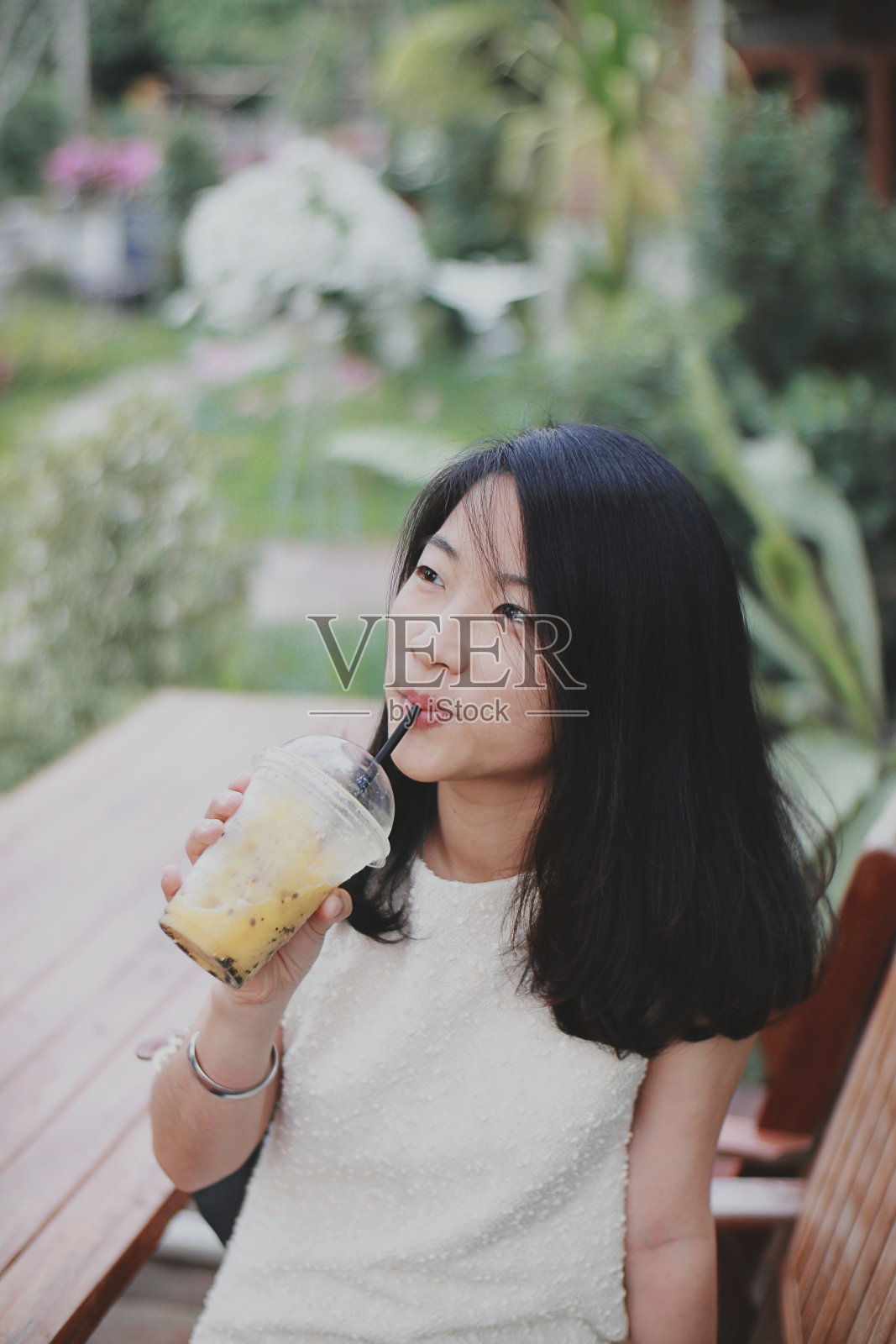 亚洲女孩在花园里喝果汁照片摄影图片