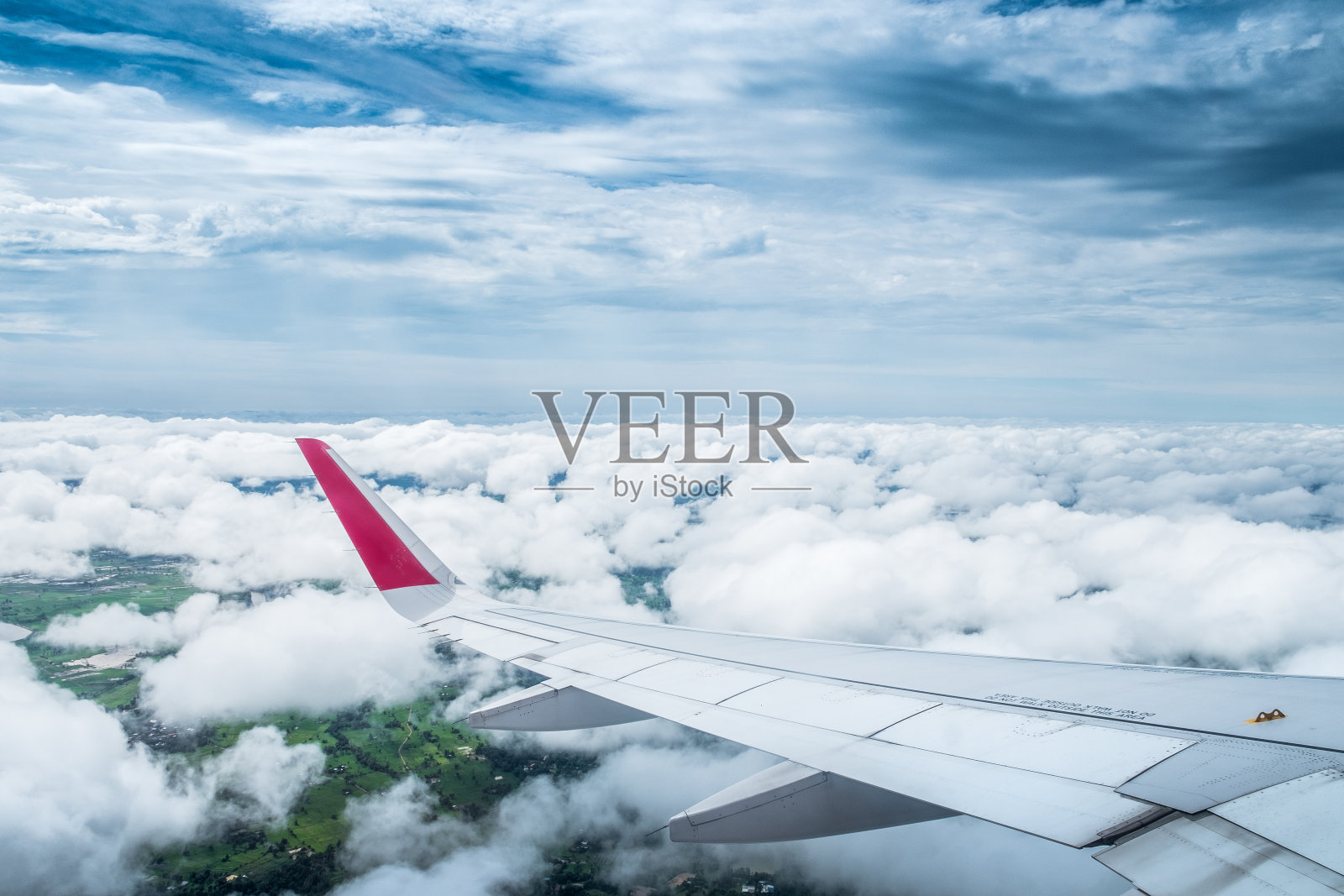 从飞机窗口望去,一架机翼的飞机在蓝天白云之上飞翔。照片摄影图片