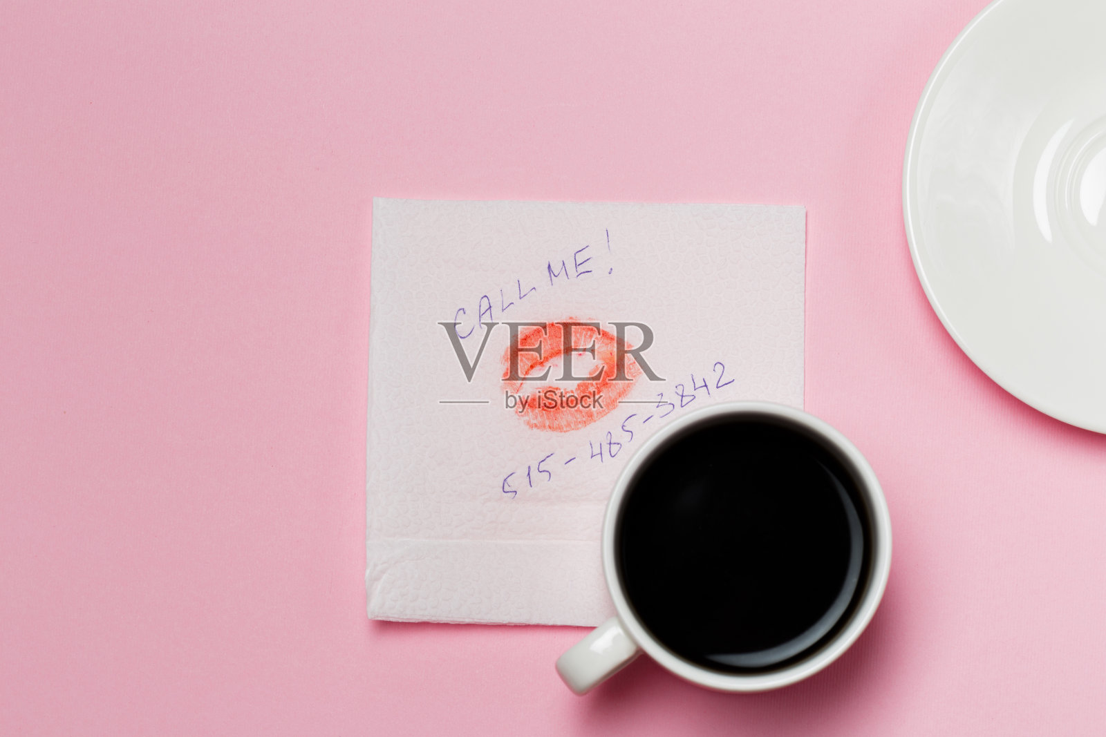 粉红色背景上有一个吻的餐巾和咖啡杯照片摄影图片