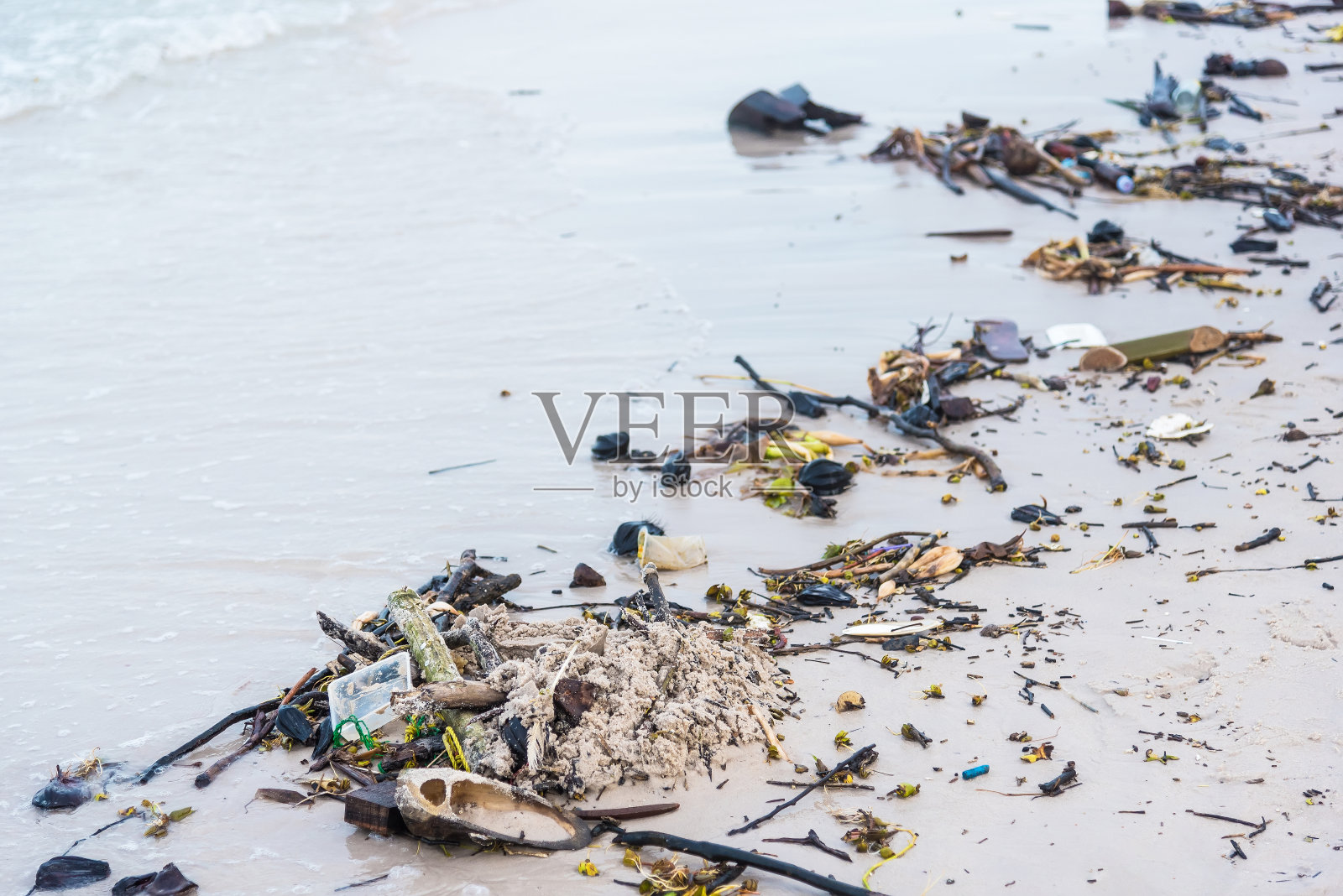 大风过后,树枝、树木、塑料垃圾从深海倾倒在沙滩上。泰国。照片摄影图片