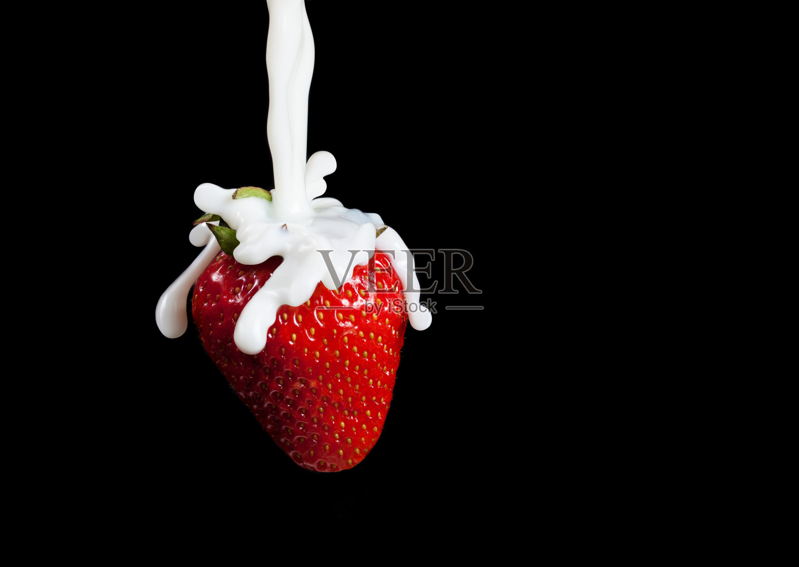 草莓溅起水花。孤立在黑色背景上。微距照片的草莓在牛奶溅和滴。照片摄影图片