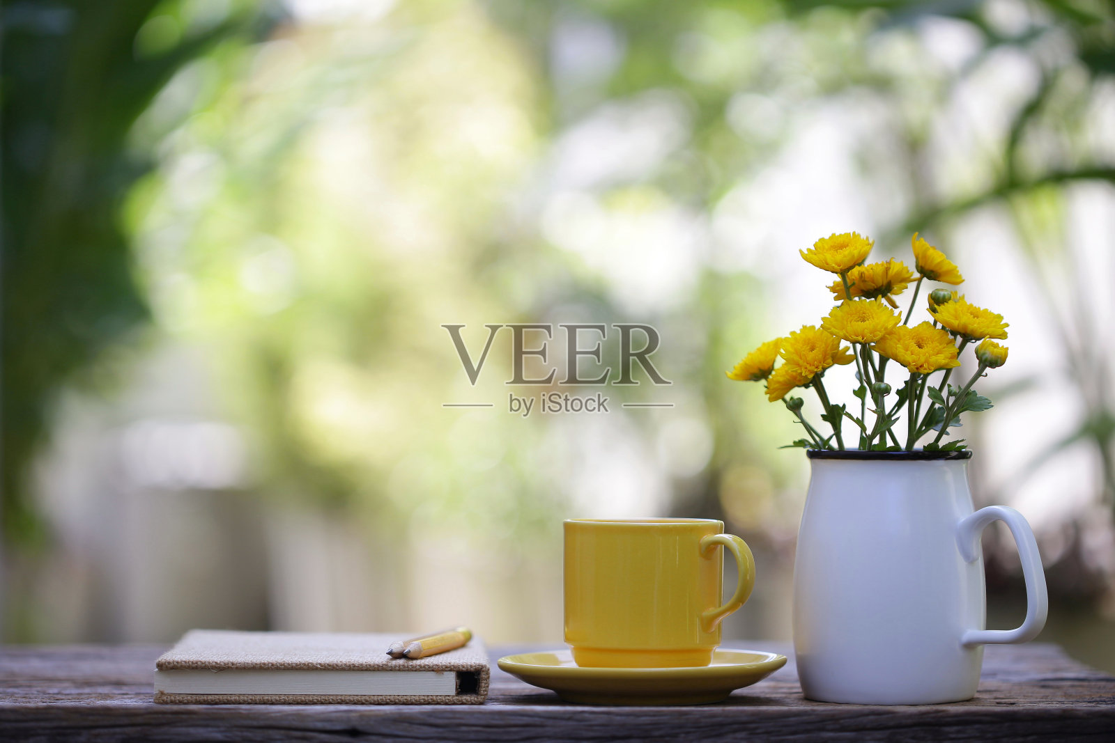 木桌上放着黄色瓷杯、花盆和笔记本照片摄影图片