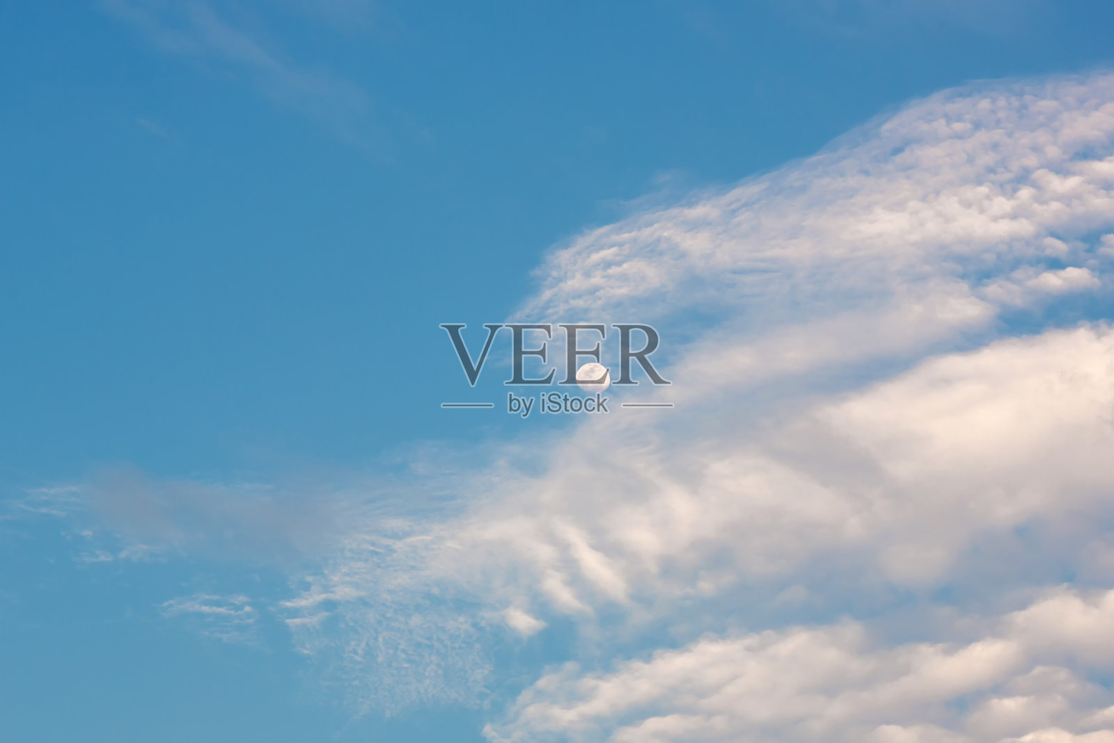 明亮的蓝色天空和半月形的月亮和云彩。夏天天空中的月亮和云。照片摄影图片