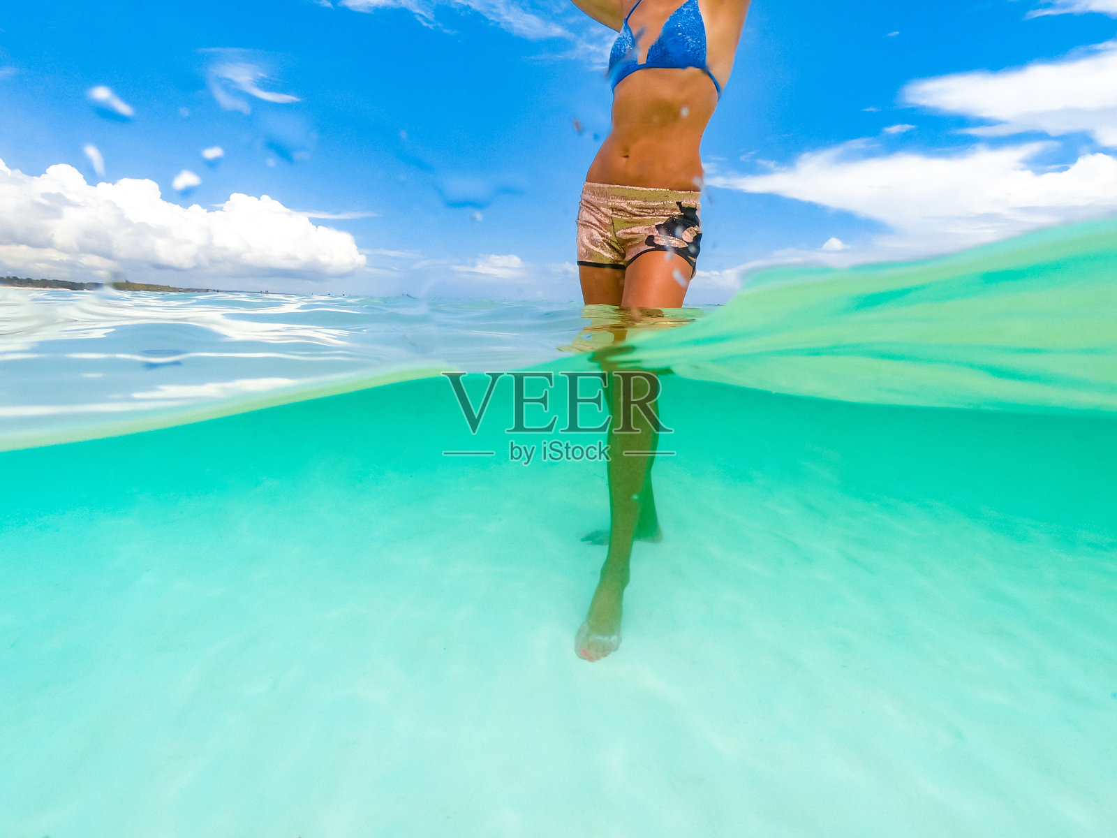 穿着比基尼站在海里的漂亮女人的腹部照片摄影图片