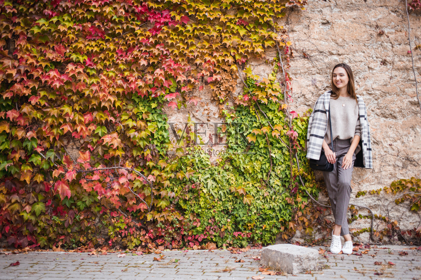 女模特在时尚的服装在街道墙上的背景照片摄影图片