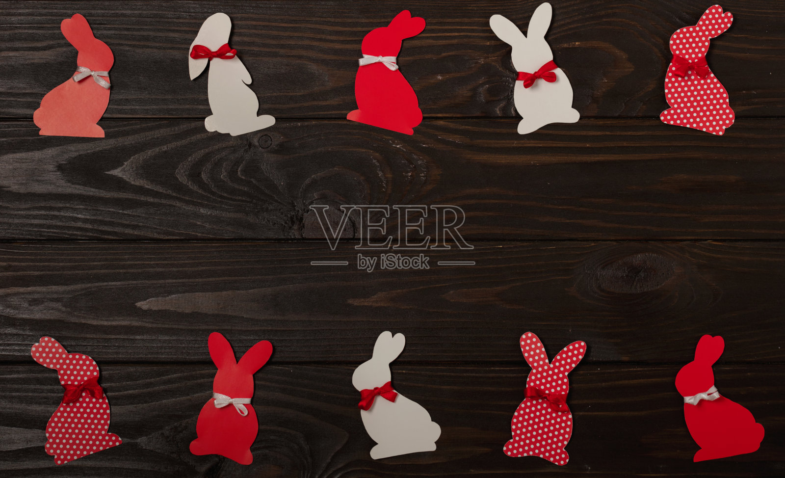 复活节快乐!复活节装饰-带丝带的复活节兔子-红色,白色和红色的白色圆点花在棕色的木制背景上。照片摄影图片