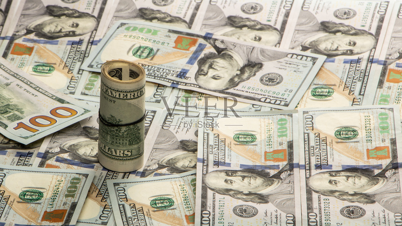 100美元的钞票拧成管子,用橡皮筋绑起来。白色背景。照片摄影图片