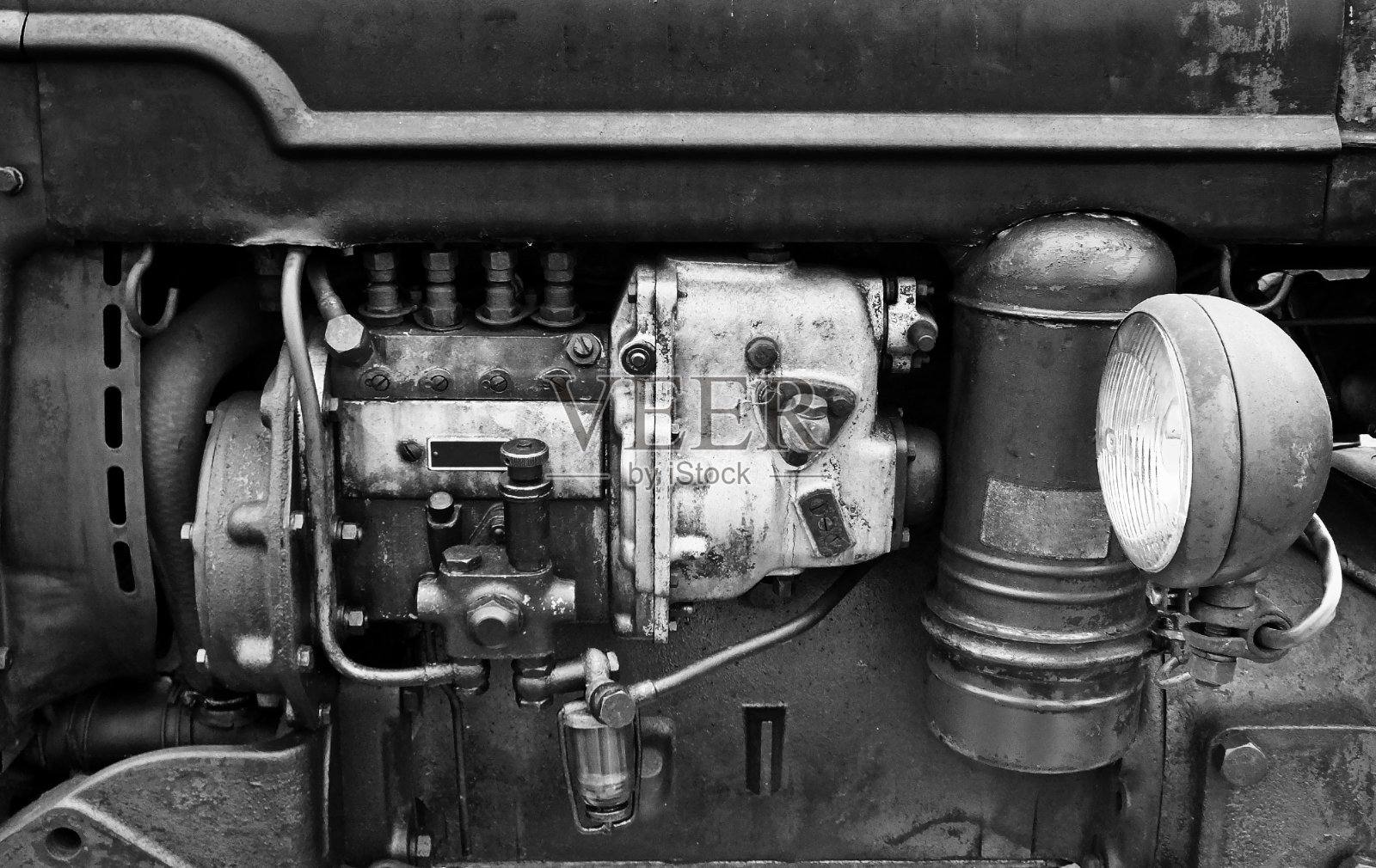 一个大型旧汽油发动机的黑白图像与锈迹和旧污渍在一个深色的农业车辆与前灯照片摄影图片