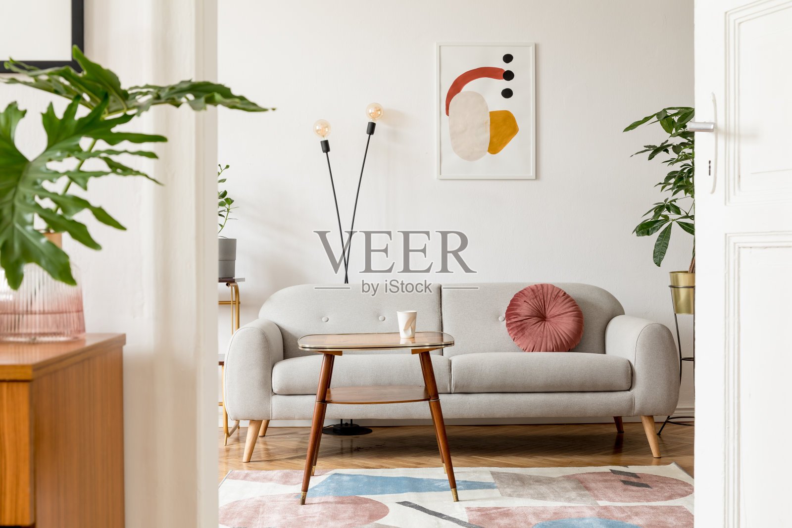 时尚复古的室内客厅设计沙发,桌子,书架和模拟海报框架在白色的墙壁上。室内设计采用棕色的木地板和植物。照片摄影图片