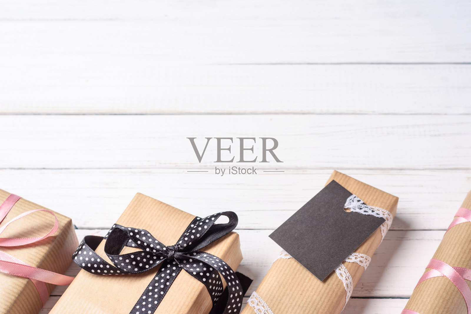 手工礼盒包装在牛皮纸与蝴蝶结在白色木制背景照片摄影图片