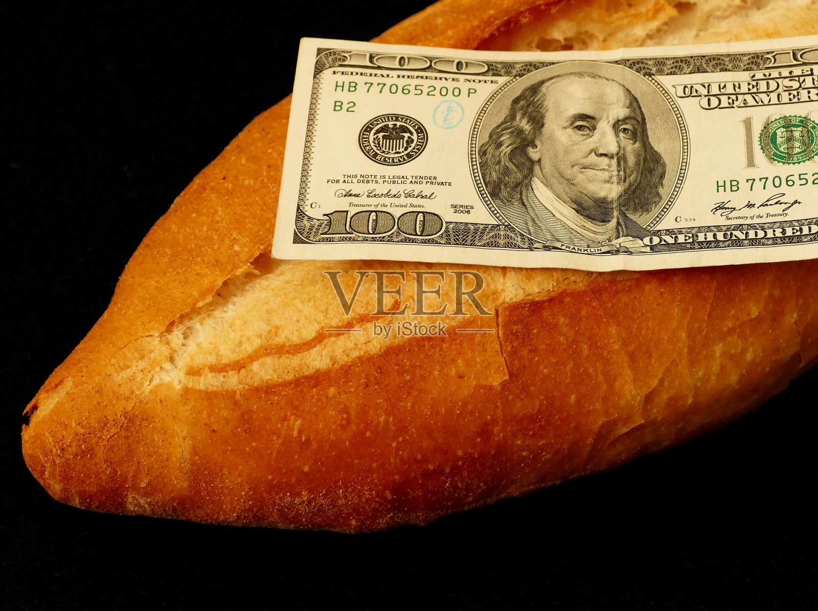 面包和100美元,新鲜烤的一整块面包,100美元旁边,关门,照片摄影图片