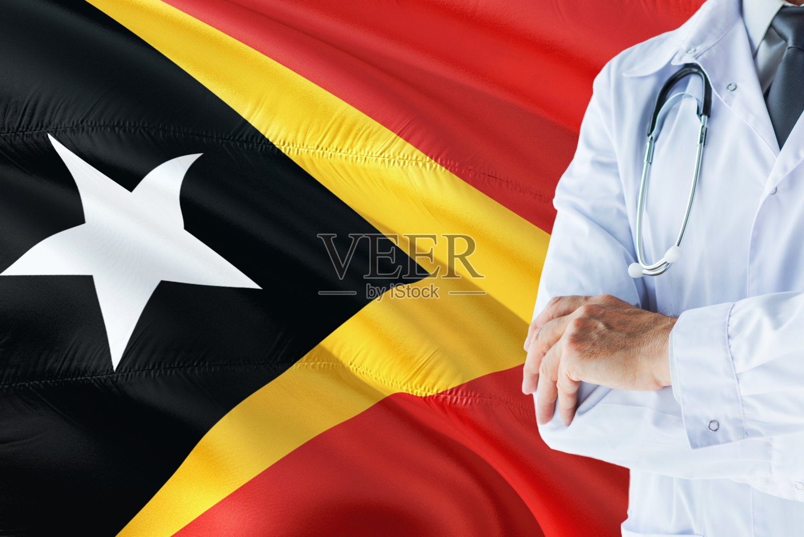 东帝汶医生站在听诊器前,背景是东帝汶国旗。国家卫生保健体系理念、医疗主题。东帝汶医生站在听诊器前,背景是东帝汶国旗。国家卫生保健体系理念、医疗主题。照片摄影图片