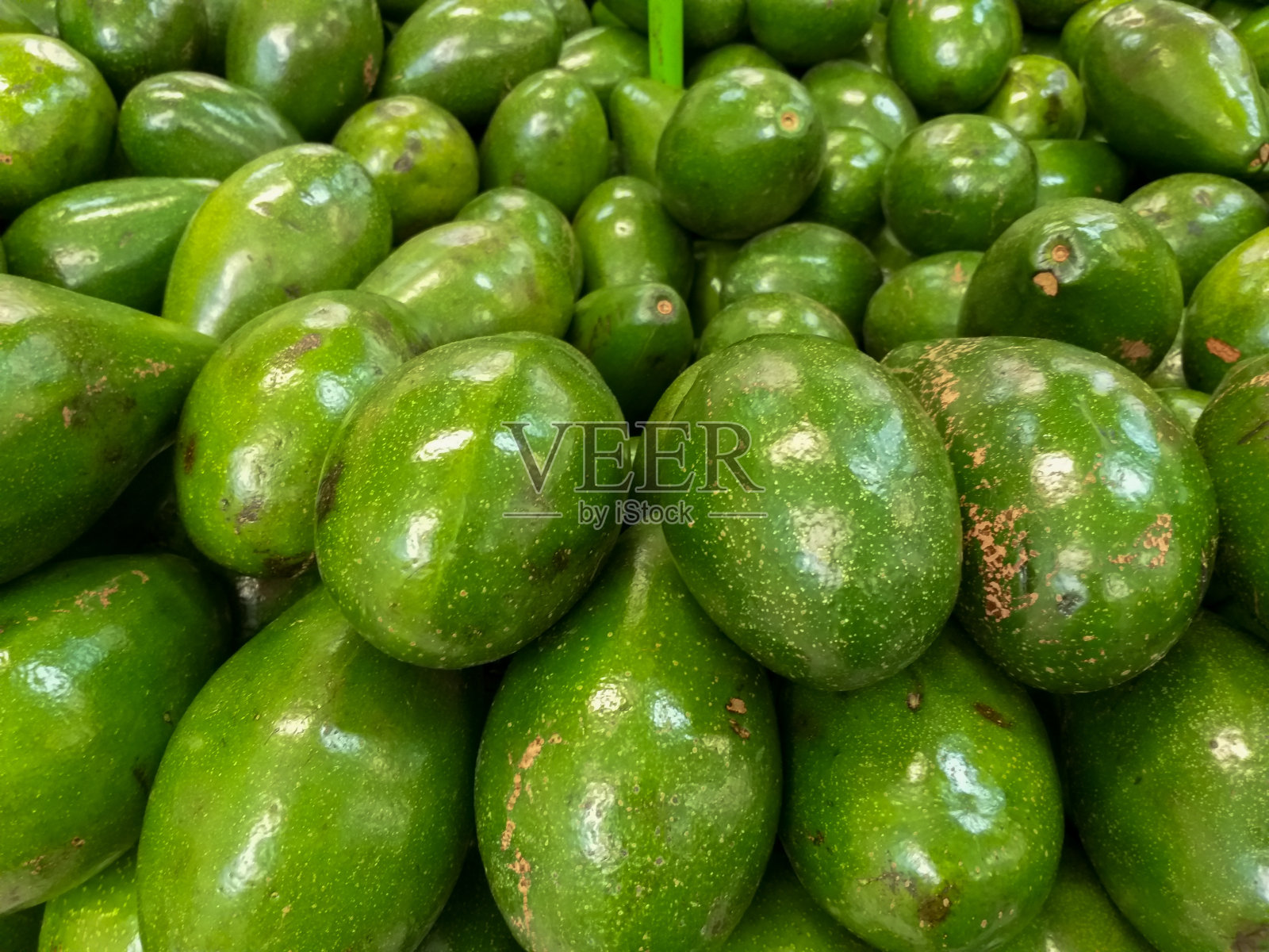 新鲜的牛油果堆在市场上出售。水果背景的文字或信息和纹理照片摄影图片