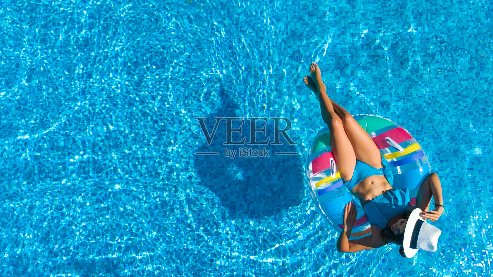 美丽的女孩戴着帽子在游泳池空中俯瞰上方,女人放松和游泳在充气圈甜甜圈上,有乐趣在水上家庭度假,热带度假胜地照片摄影图片