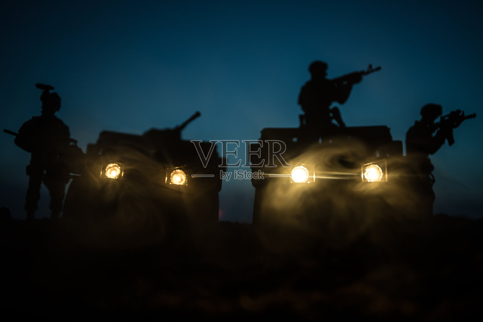 战争概念:雾天战场上的军事剪影战斗场景,云天下夜空下的战斗剪影,军队车辆与士兵照片摄影图片