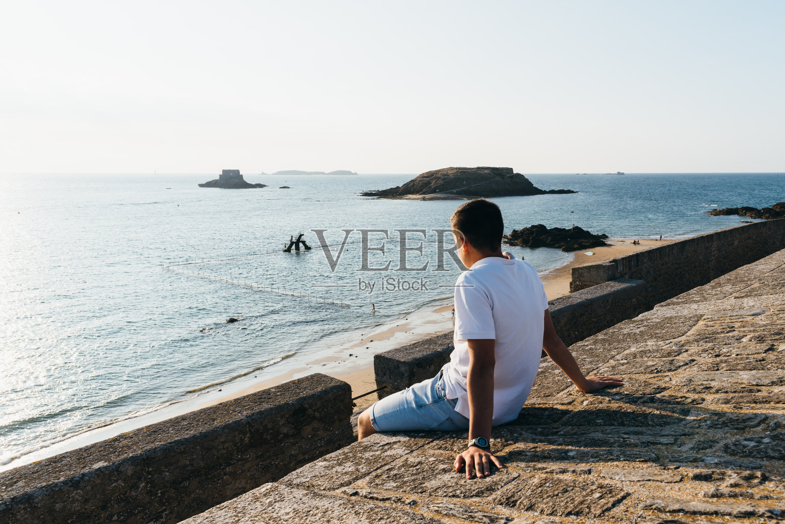 一个年轻人正在圣马洛湾看日落照片摄影图片