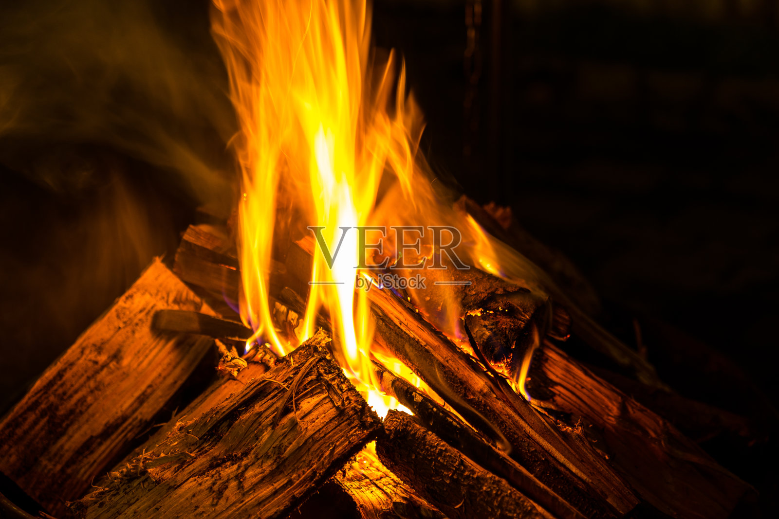 在黑暗的夜晚,木坯的火焰发出温暖的橙色光芒照片摄影图片