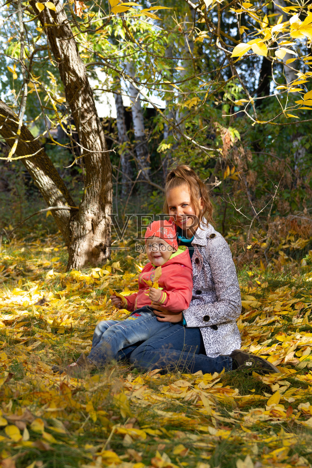 妈妈和宝宝在公园里秋叶的背景下照片摄影图片
