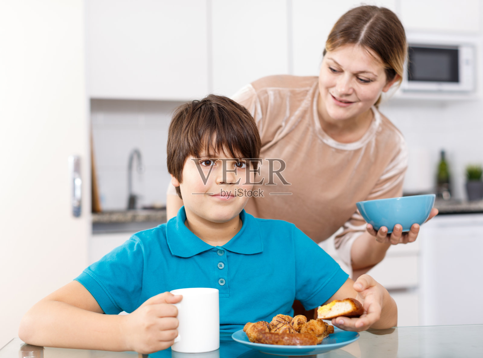 母亲和儿子在厨房吃饭照片摄影图片