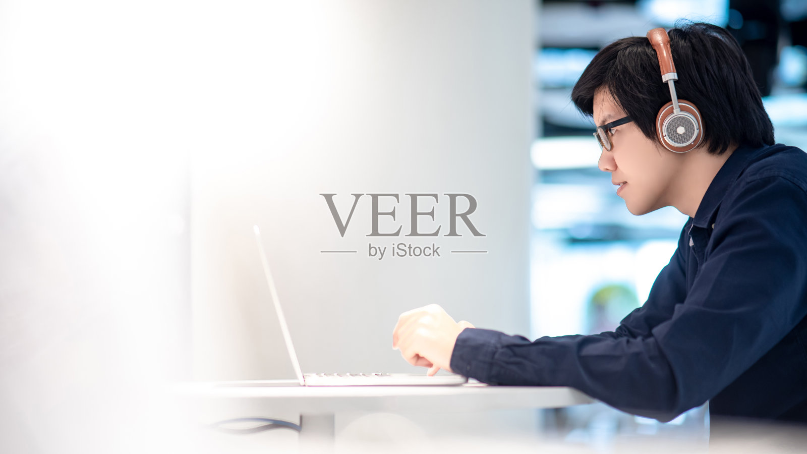 亚洲商人听音乐耳机与笔记本电脑在共同的工作空间。自由职业者或数字游牧民的生活方式。网上购物或网上电子商务社交媒体照片摄影图片