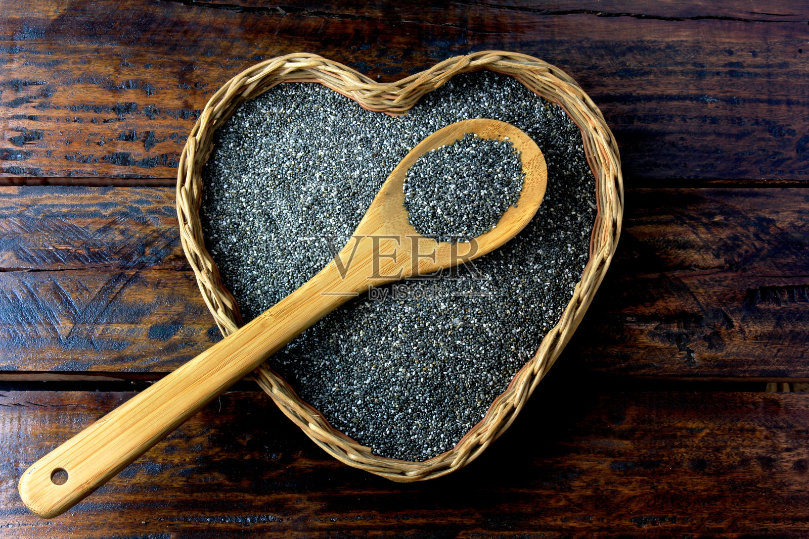 奇花异草种子在篮子里与心的形状孤立在乡村桌子旁边的勺子。俯视图照片摄影图片