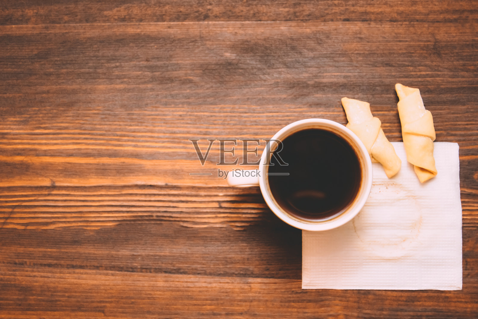 白色餐巾上的一杯咖啡,木质背景上还有饼干照片摄影图片