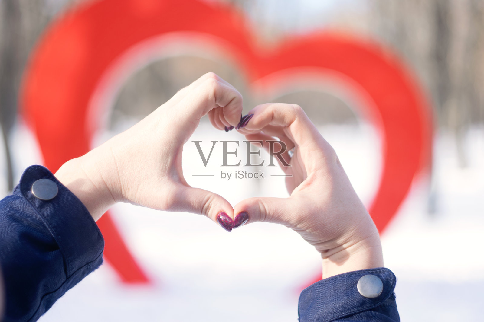 女性的手在心形的大背景下安装在冬日公园的红心街。爱情,浪漫,情人节的概念照片摄影图片