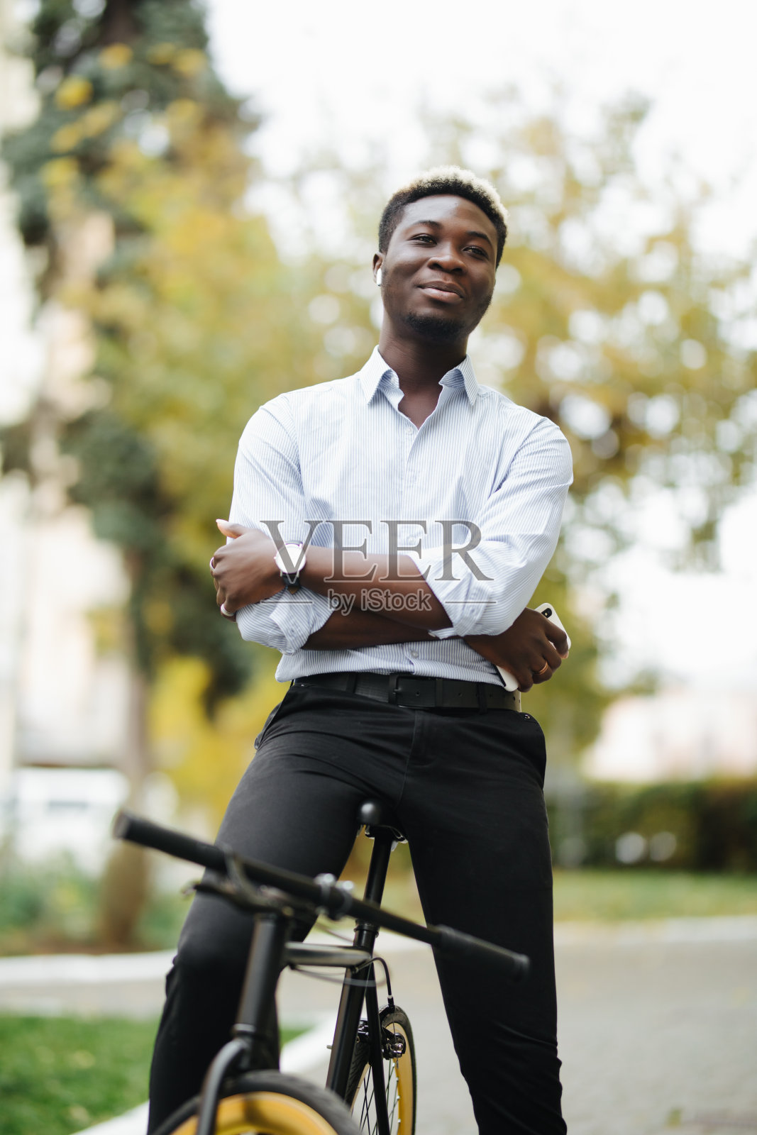 英俊的非洲男人的肖像和使用他的手机在街上。照片摄影图片